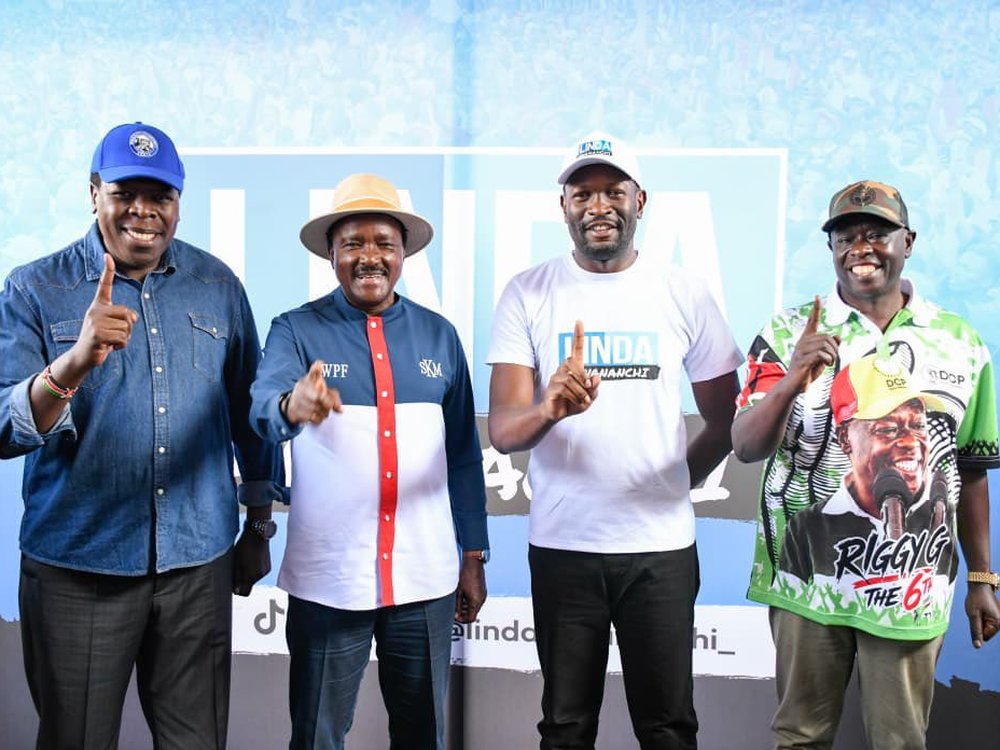 Four opposition leaders smiling and raising one finger in front of a blue Linda Mwananchi banner